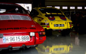 Two Porsche 911 racing cars in the pit garage.